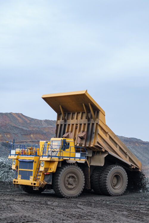 A Large Yellow Dump Truck Unloads Minerals.